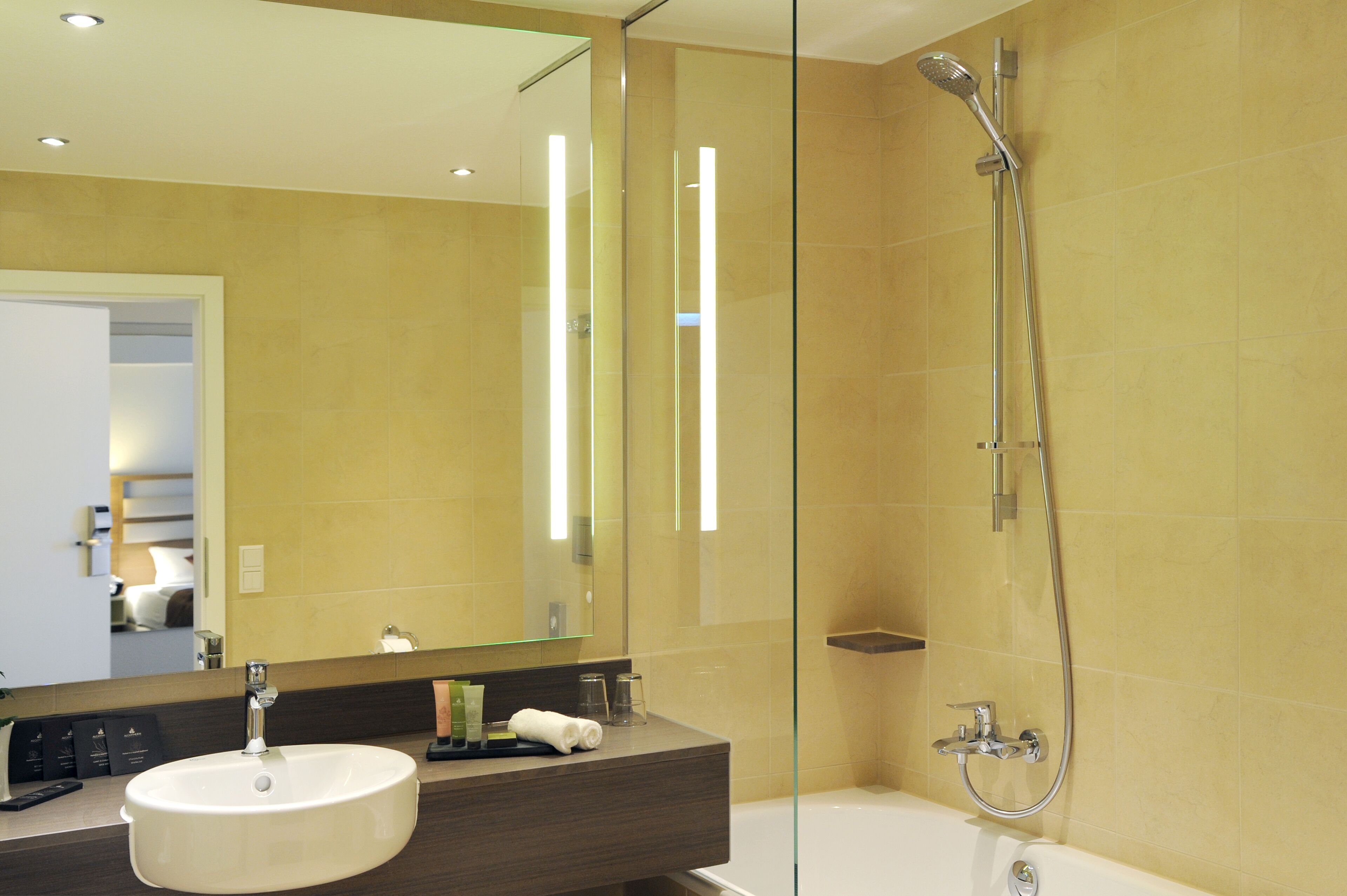Un bagno moderno con uno specchio grande, un lavandino, una doccia e un box doccia in vetro.