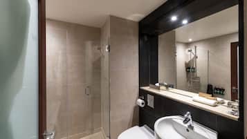 A modern bathroom with a glass-enclosed shower, a white sink, and a large mirror.