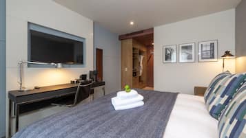 Une chambre d’hôtel moderne dotée d’un grand lit, d’un bureau avec un ordinateur, d’une télévision à écran plat et d’une armoire.