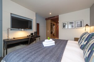 Une chambre d’hôtel moderne dotée d’un grand lit, d’un bureau avec un ordinateur, d’une télévision à écran plat et d’une armoire.