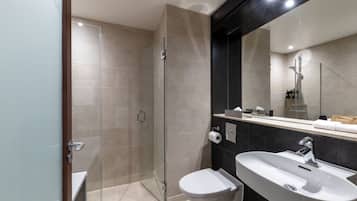 A modern bathroom with a glass shower enclosure, a white sink, and a large mirror.