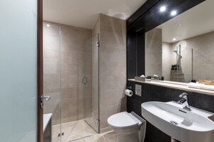 A modern bathroom with a glass shower enclosure, a white sink, and a large mirror.