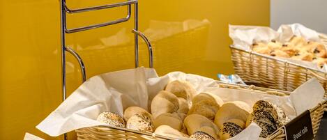 Una variedad de productos horneados como croissants, bollos de pan y un bizcocho de plátano y coco.