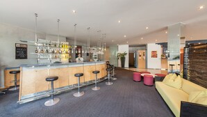 Un área de bar moderna con mostrador, taburetes y una variedad de botellas.