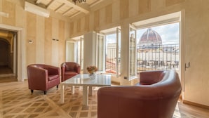 Una habitació àmplia amb un gran finestral que ofereix vistes a una cúpula i una terrassa. Hi ha un taulell blanc i dues cadires vermelles.