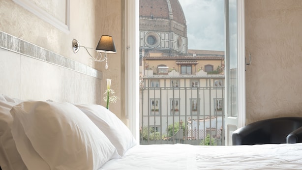 Habitació d'hotel amb un llit, una làmpada i vista d'un edifici amb cúpula.