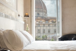 A hotel room with a bed, a lamp, and a view of a building with a dome.