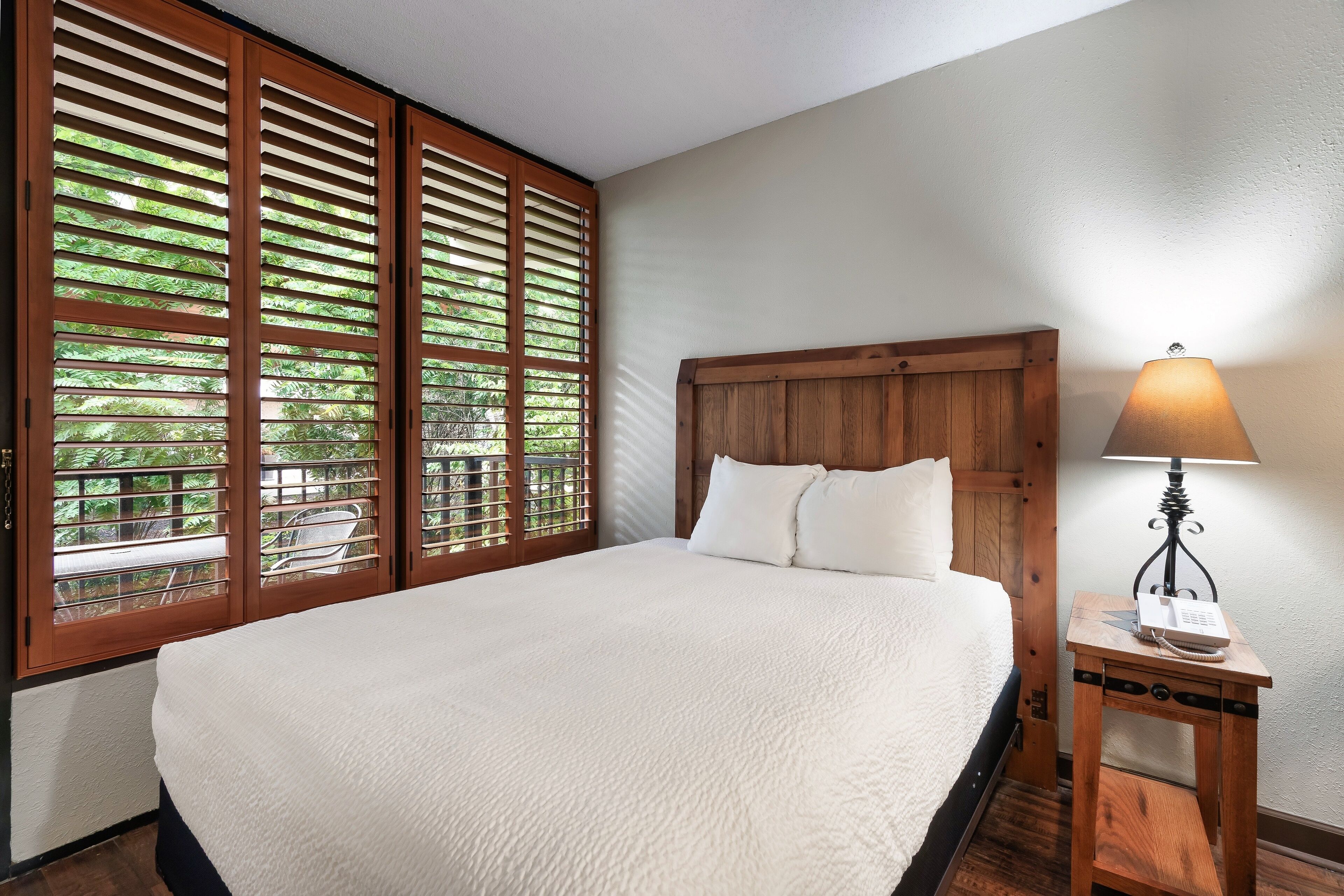 A bedroom with a large bed, wooden headboard, and a bedside table with a lamp.