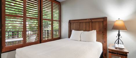 A bedroom with a large bed, wooden headboard, and a bedside table with a lamp.