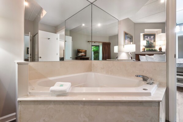 Un baño moderno con una bañera independiente grande, un espejo y un tocador con lavabo.