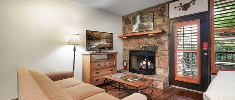 Un salon avec une cheminée en pierre, des meubles en bois et un tableau accroché au mur.