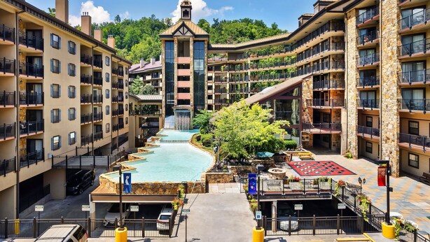 A multi-story hotel with balconies, a central water feature, and a stone facade. - Gatlinburg Town Square (Gatlinburg)