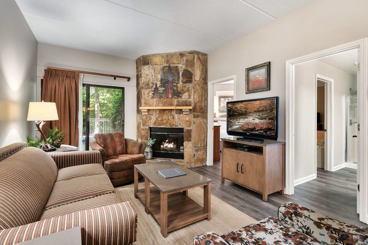 A living room with a stone fireplace, a television, and a sofa.