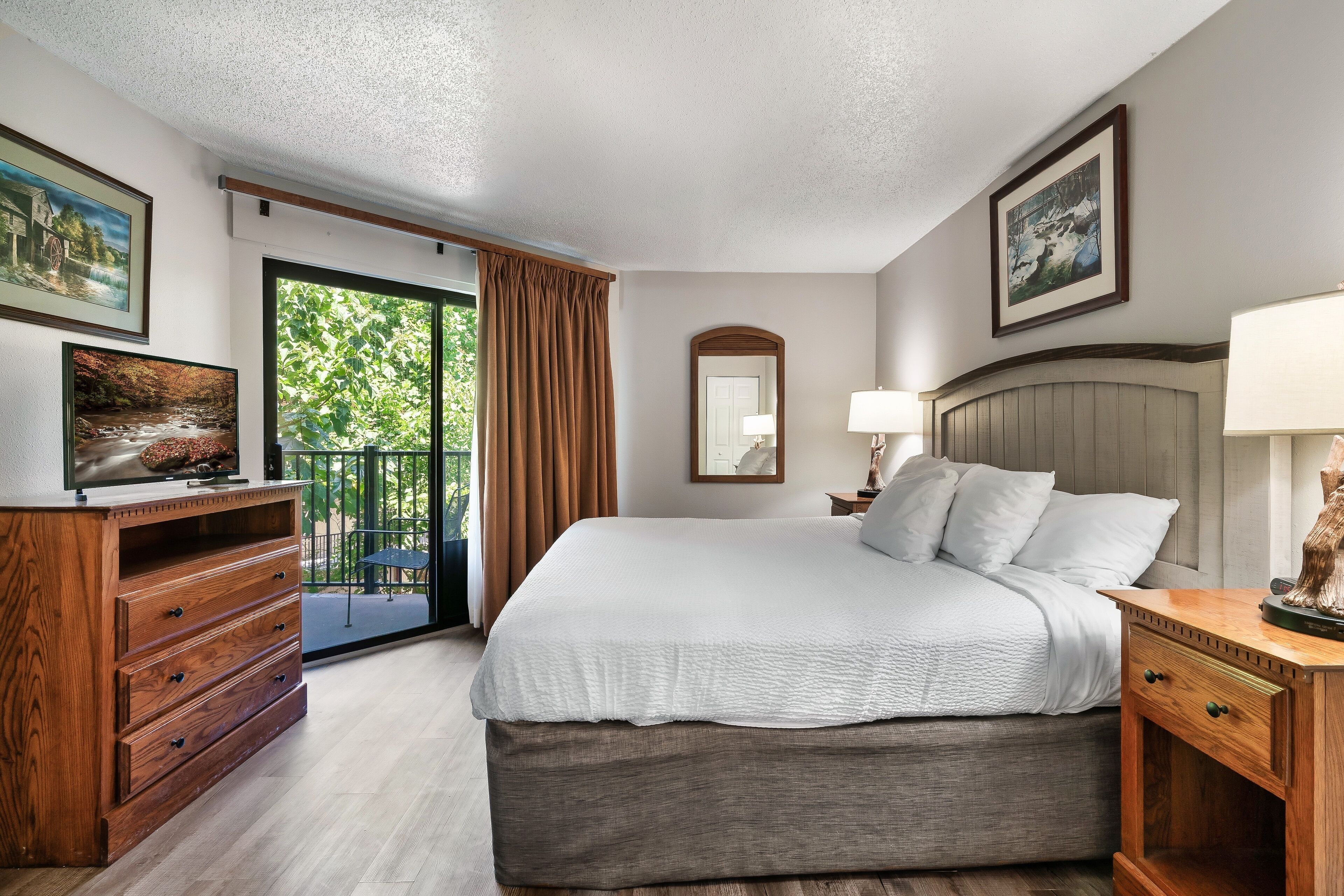 Un dormitorio con una cama grande, cómoda de madera y vistas a un balcón.