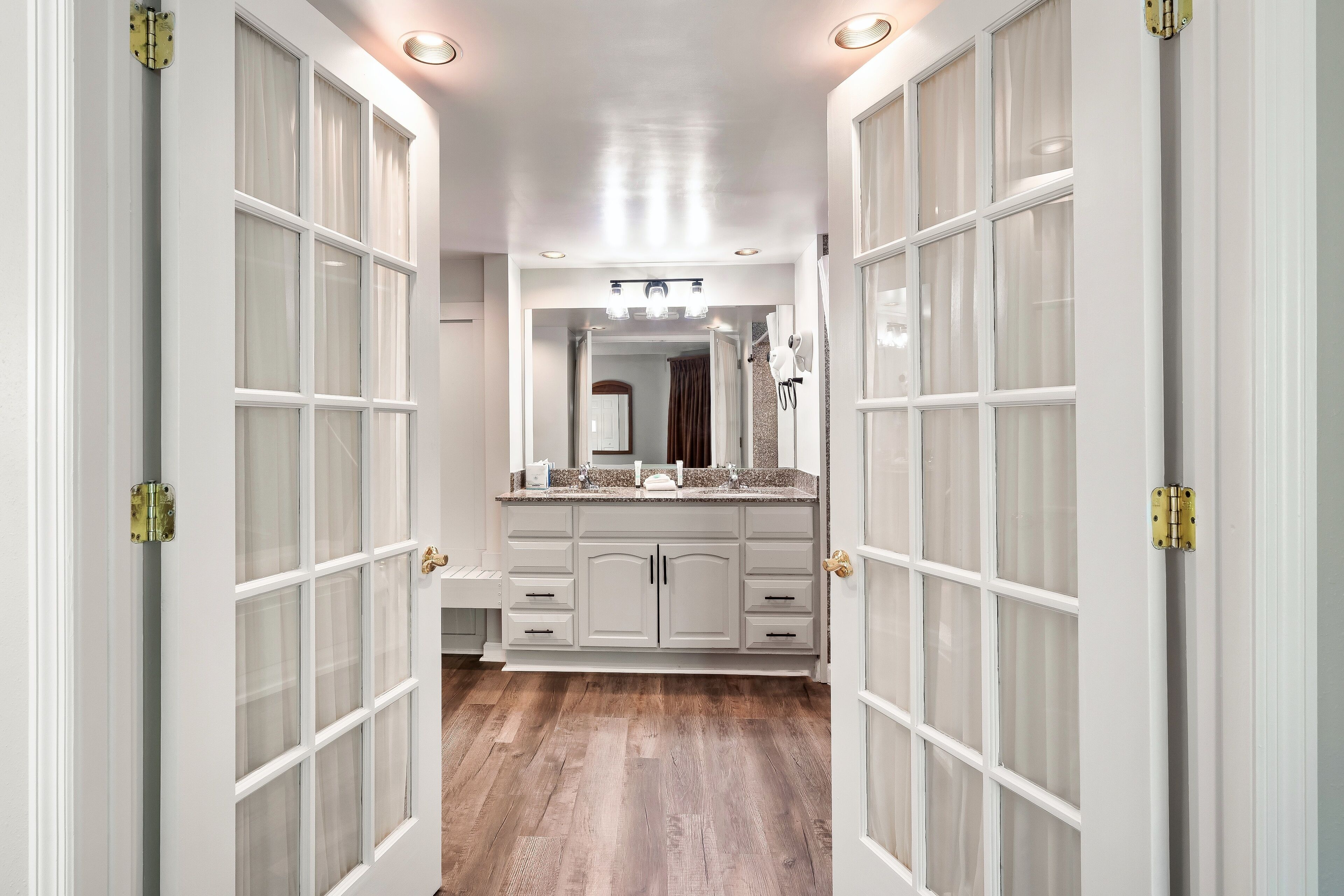 A hallway with a vanity, a mirror, and a door with glass panels.