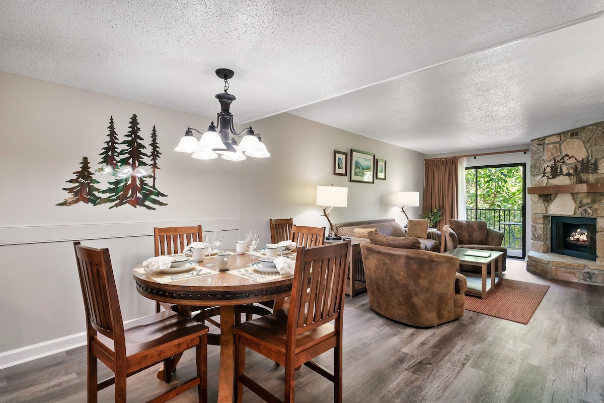 A dining area with a round table and chairs, a fireplace, and a seating area with a sofa and armchairs.