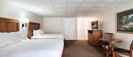 A hotel room with two beds, a desk, a chair, a lamp, and a painting on the wall.