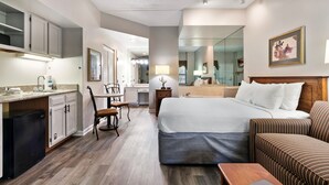 A hotel room with a bed, a small sofa, a desk with a chair, a kitchenette, and a bathroom. - Gatlinburg Town Square (Gatlinburg)
