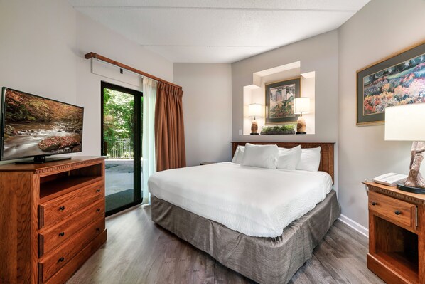 Habitación de hotel con cama, cómoda de madera, televisión y obras de arte en las paredes.