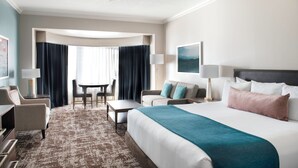Una habitación de hotel con una cama grande, un escritorio, una silla, un sofá y una mesa de comedor.