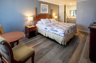 Una habitación de hotel con una cama, mesitas de noche, una silla y un escritorio.