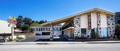 Un motel avec une façade en pierre, un panneau indicateur et un parking.