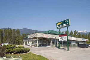 Un Sandman Inn con techo verde, una oficina visible y un cartel que indica que admite mascotas.