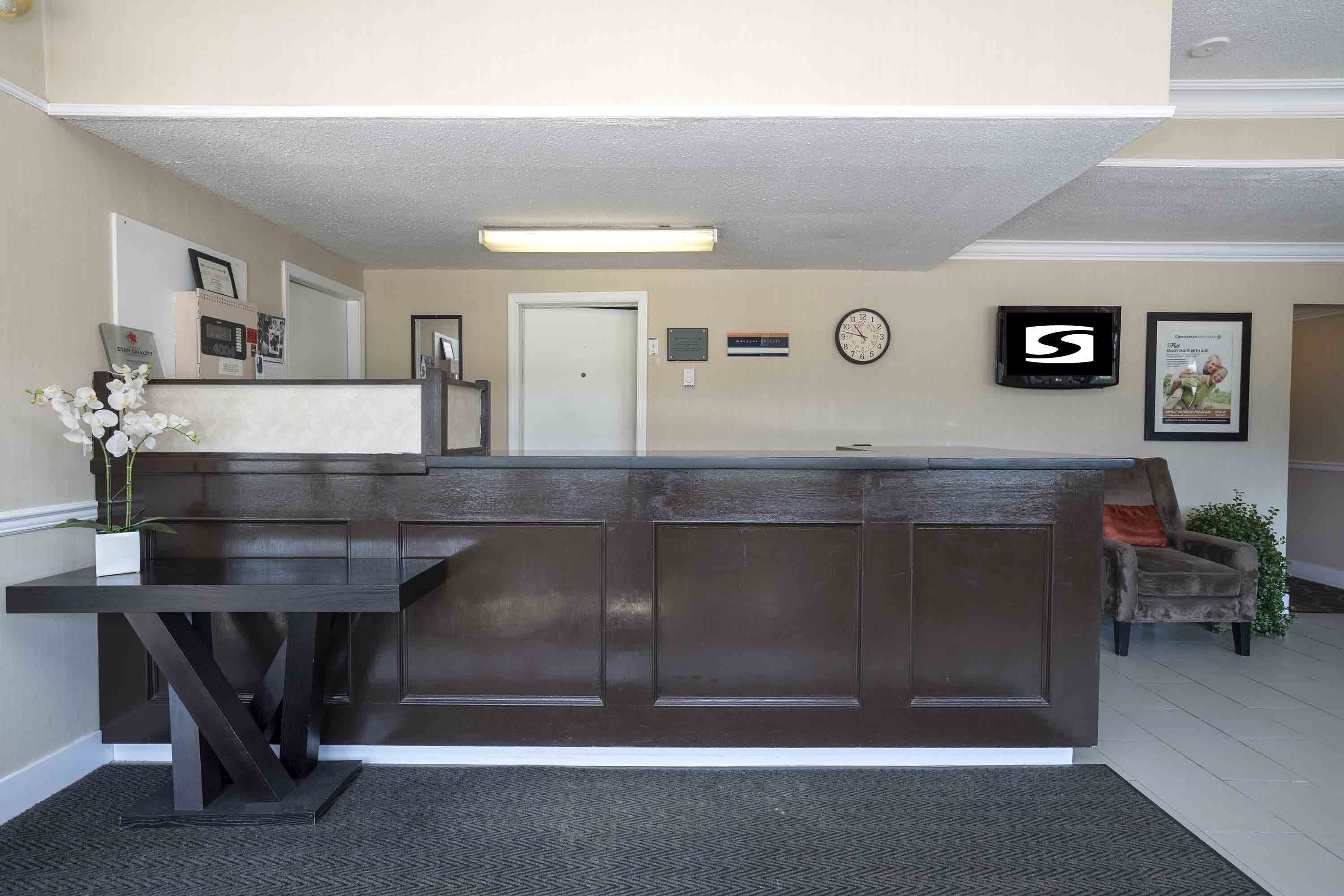 A reception area with a dark wooden desk, a clock, and framed pictures on the wall.