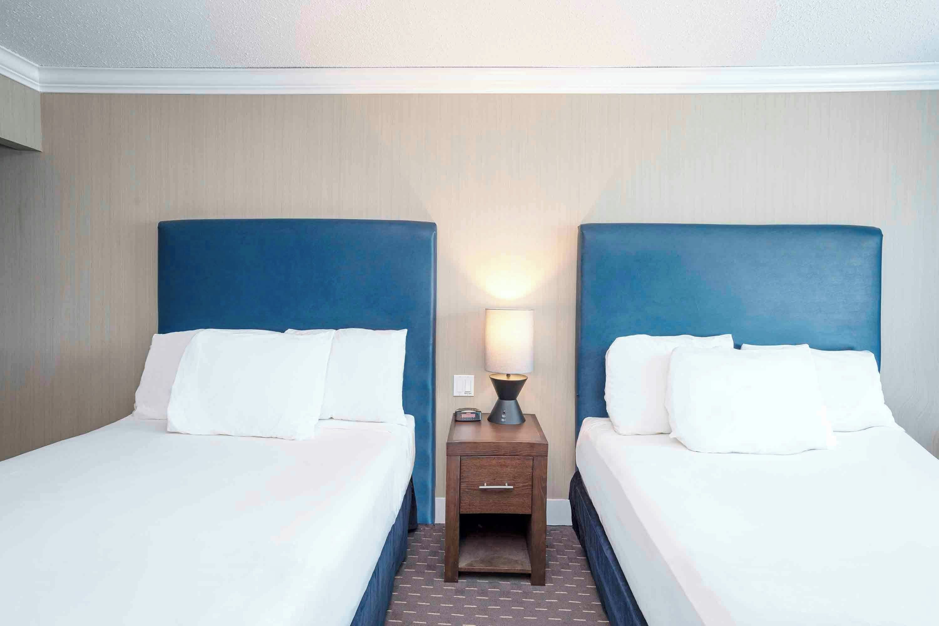 Ein Hotelzimmer mit zwei Betten, einem Nachttisch und einer Lampe.