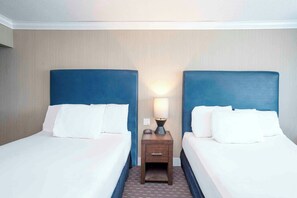 A hotel room with two beds, a nightstand, and a lamp. - Sandman Inn Blue River (Blue River)
