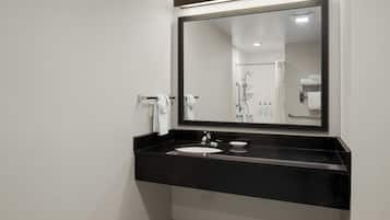 Un baño moderno con encimera negra, lavabo blanco y un espejo grande.