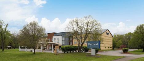 A Fairfield by Marriott hotel with a large sign, a parking lot, and surrounding greenery.