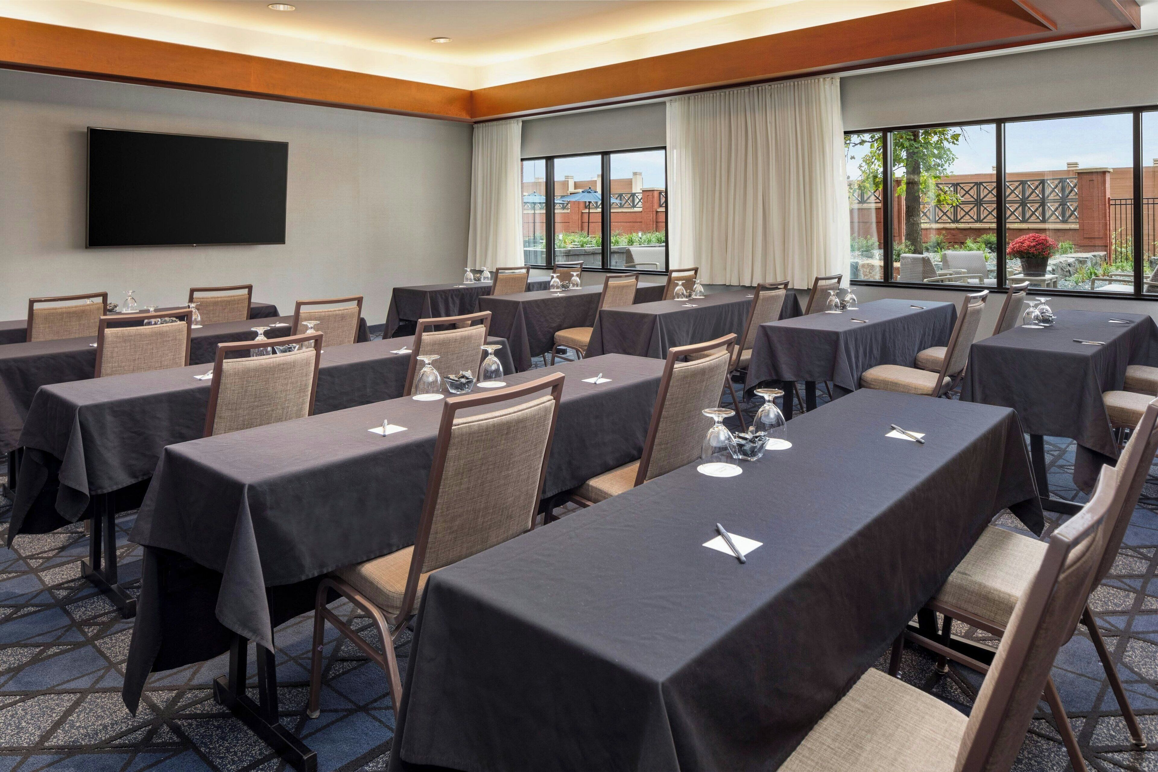 Un salón de conferencias con varias mesas, sillas y una pantalla grande.