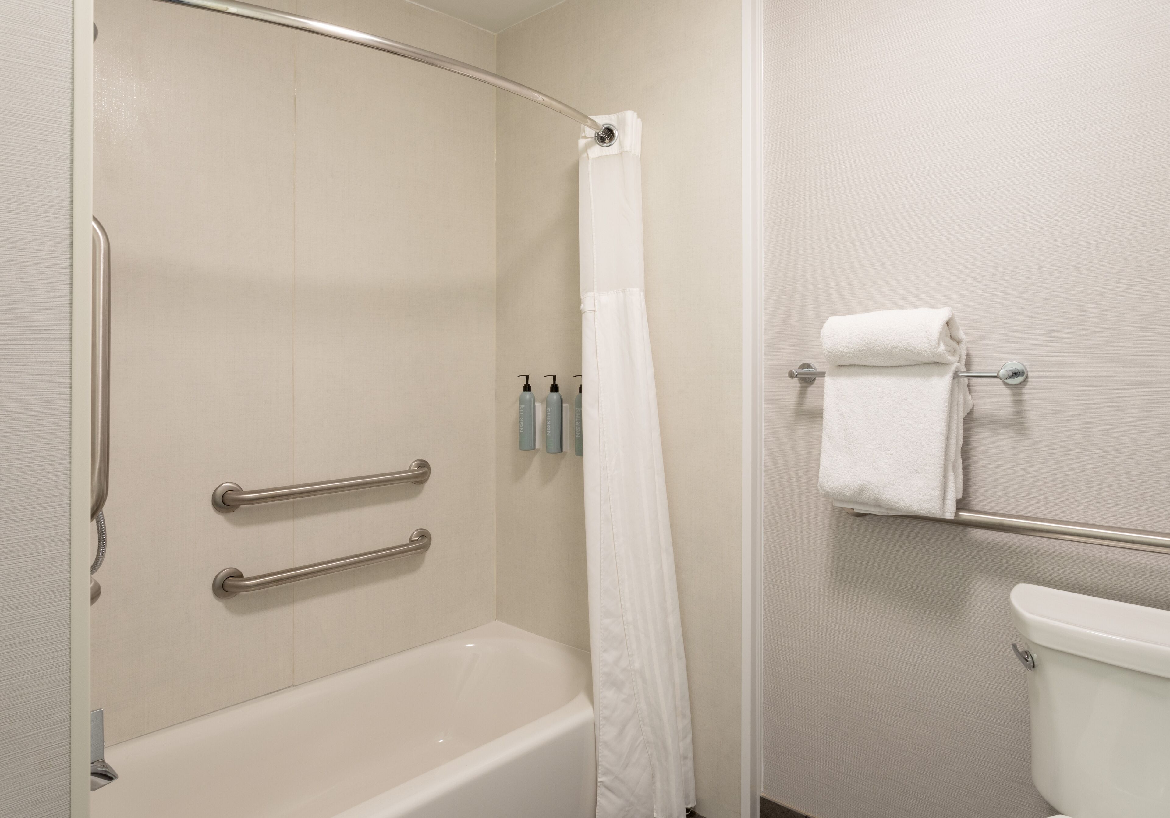 A bathroom with a bathtub, a shower curtain, a towel rack, and a toilet.