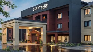 A Courtyard by Marriott hotel with a modern architectural design, featuring a covered entrance and a well-lit facade.