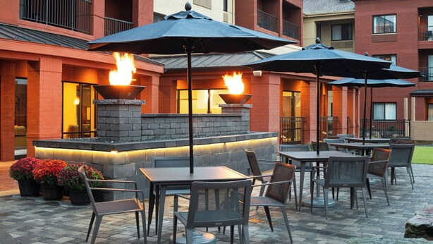 An outdoor patio with tables and chairs, a fire feature, and potted plants.