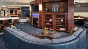 A modern hotel lobby with a curved seating area, a bar, and a fireplace.