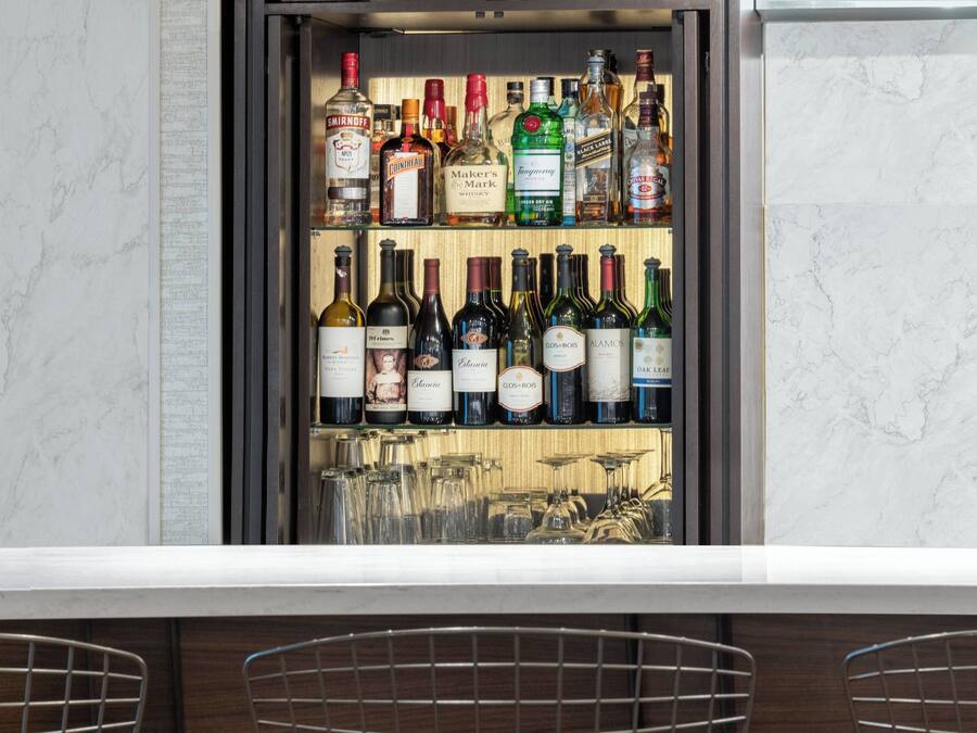 A bar area with shelves of various liquor bottles and wine glasses.