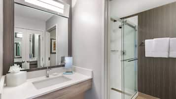 Un baño moderno con un espejo grande, un lavamanos, una cabina de ducha de vidrio y un perchero para toallas.