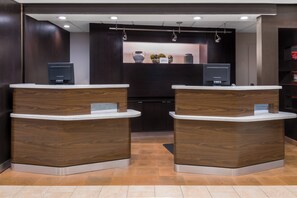 A reception area with two wooden reception desks, a dark wall, and a shelf with decorative items.