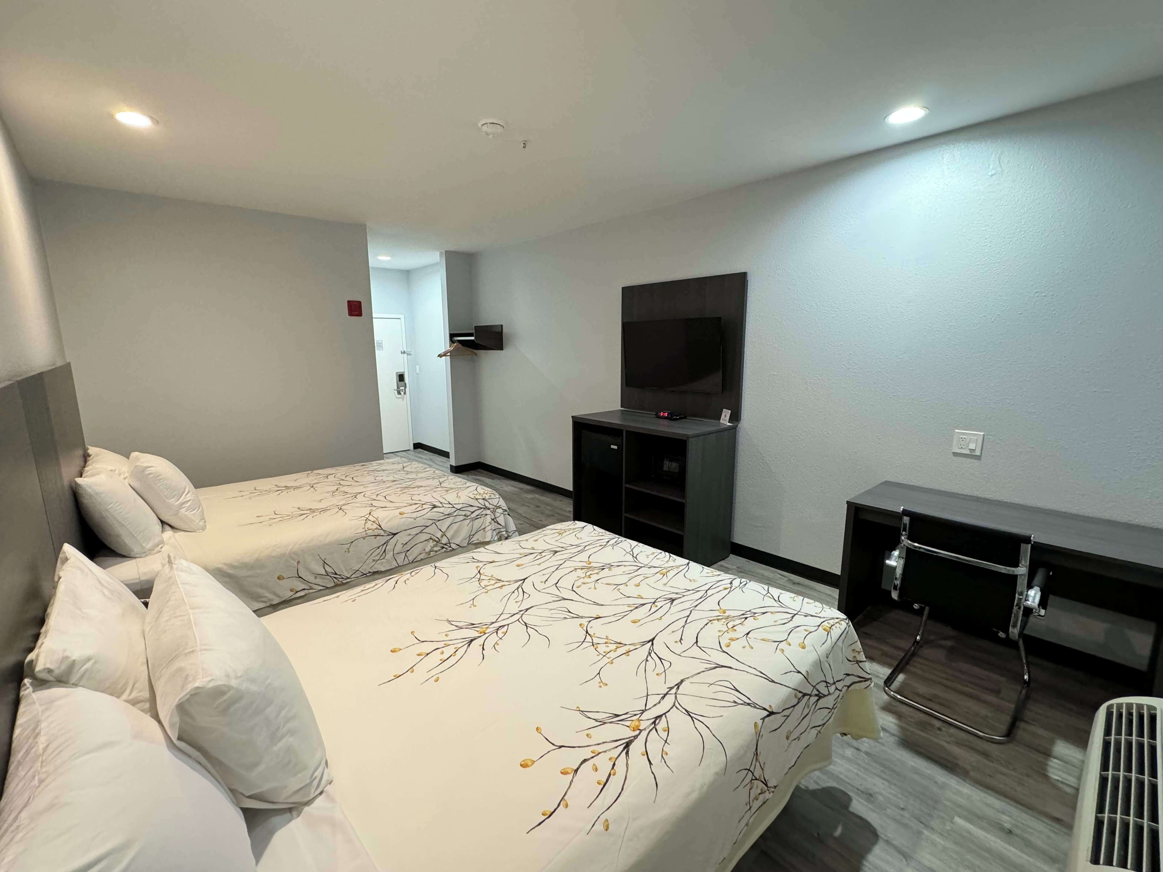 Una habitación de hotel con dos camas, televisión, escritorio y vestidor.