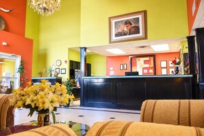A reception area with a black reception desk, a chandelier, and a framed picture on the wall.