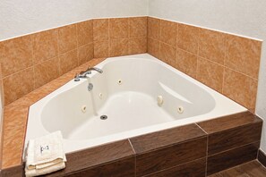 Une salle de bain d’angle avec une baignoire sur pieds, une serviette et des carreaux marron.