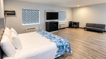 A hotel room with a bed, a TV, a sofa, and a desk.