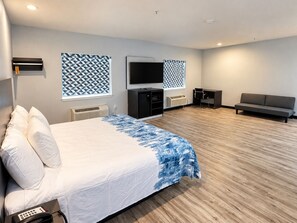 Une chambre d’hôtel avec un lit, une télévision, un canapé et un bureau.