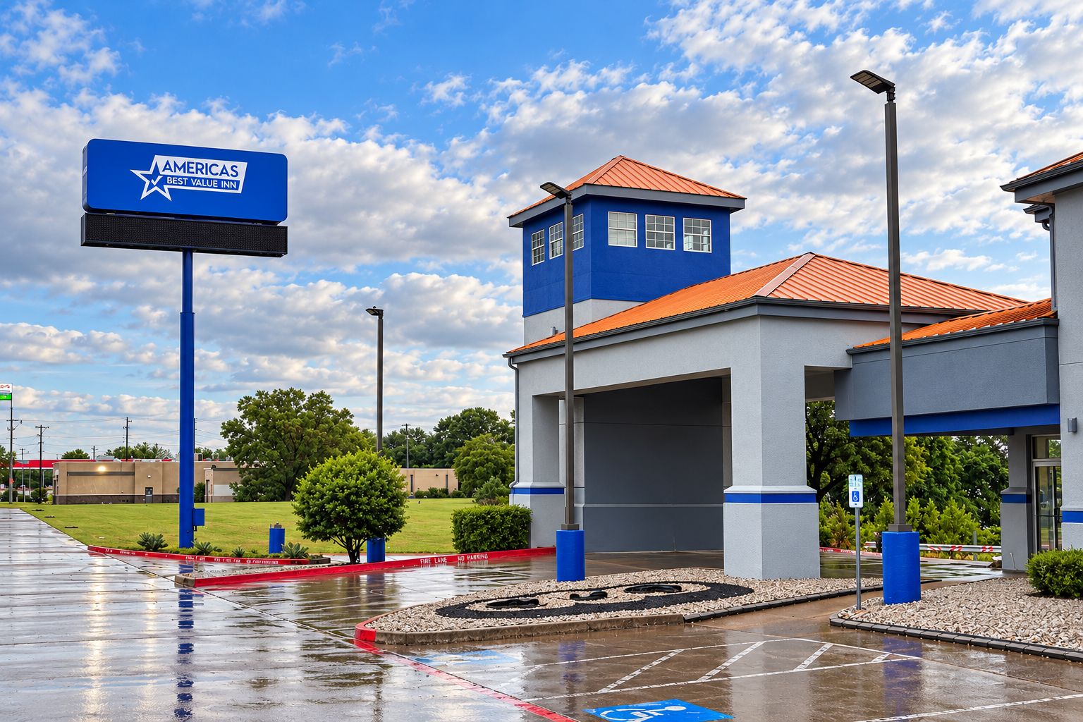 A hotel with a blue and white exterior, a parking lot, and a clear sky.