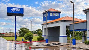 A hotel with a blue and white exterior, a parking lot, and a clear sky.