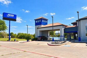 A hotel with a blue and white exterior, a parking lot, and a signboard.
