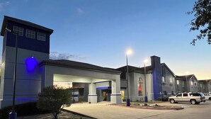 A building with a blue and white facade, a fire lane, and a parking area. - Americas Best Value Inn & Suites Haltom City Ft. Worth (Haltom City)