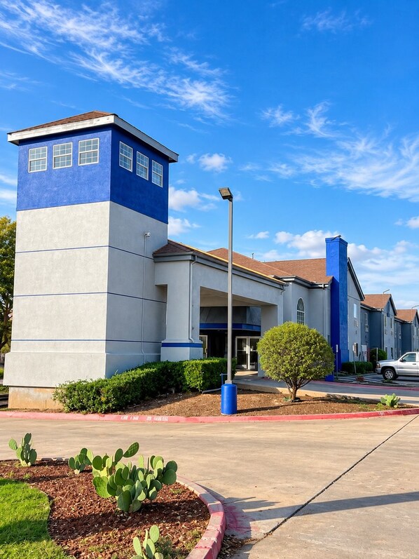 A building with a blue and white facade, a clear sky, and a parking lot.